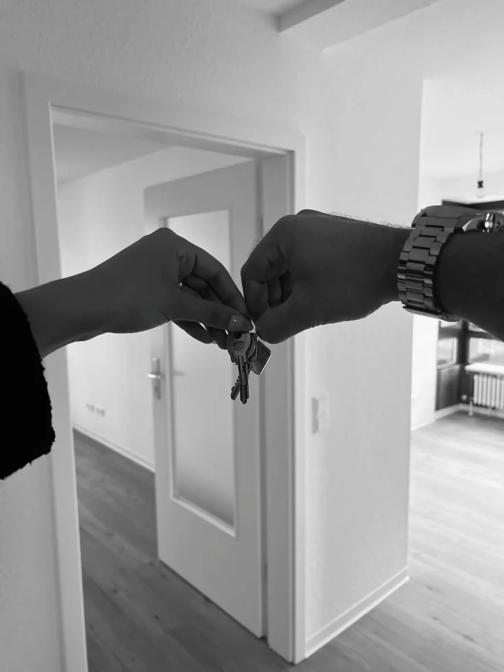 A hand passes a set of keys to another at the doorway of a freshly painted home.