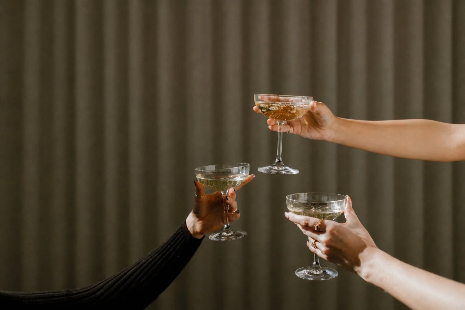 Three coupe glasses meet in a quiet toast.